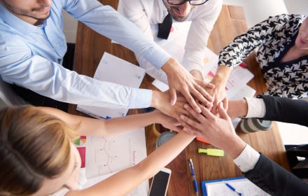 stack of human hands above the table